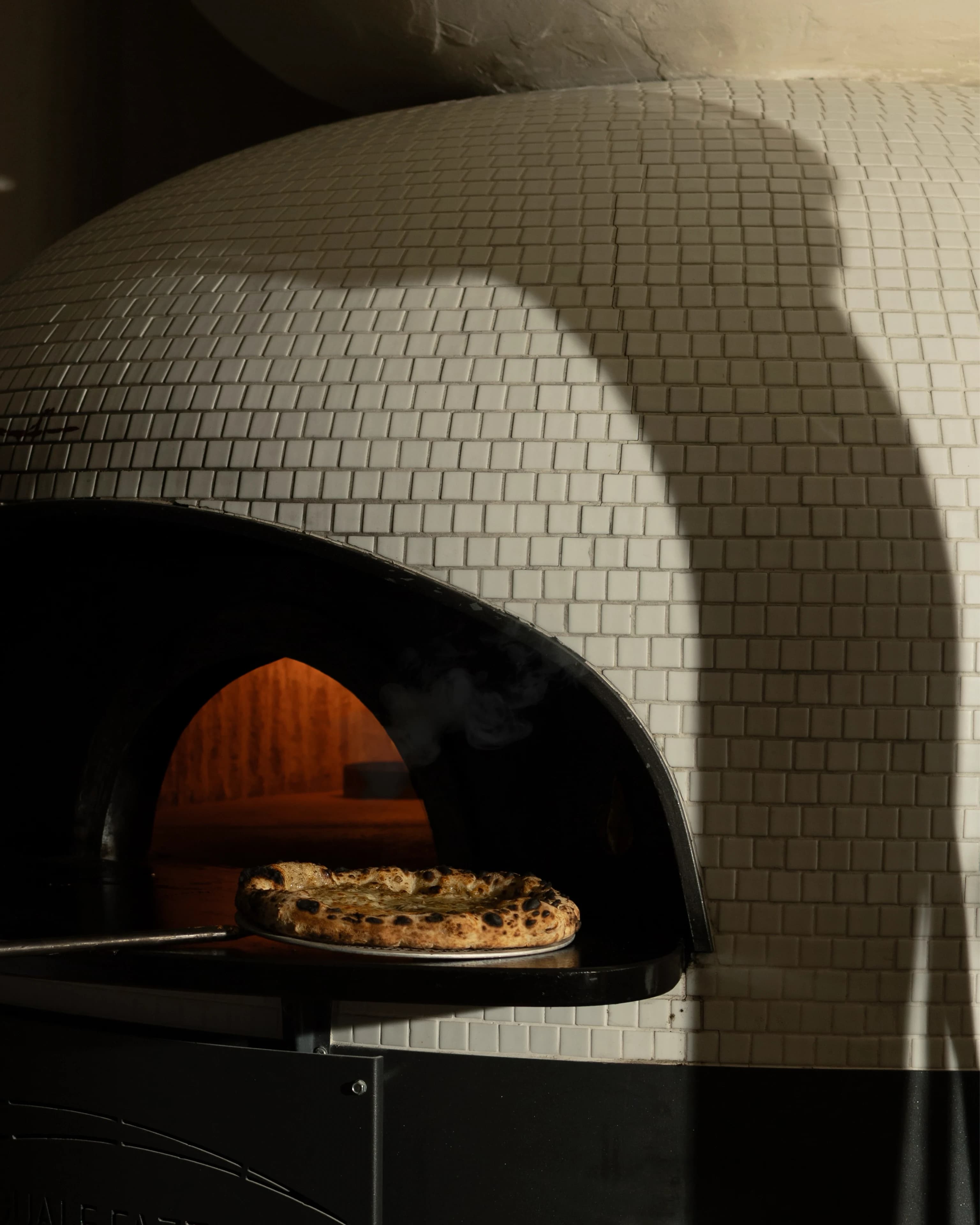 A hand-tossed MEMOS pizza fresh from the tiled wood-fired oven