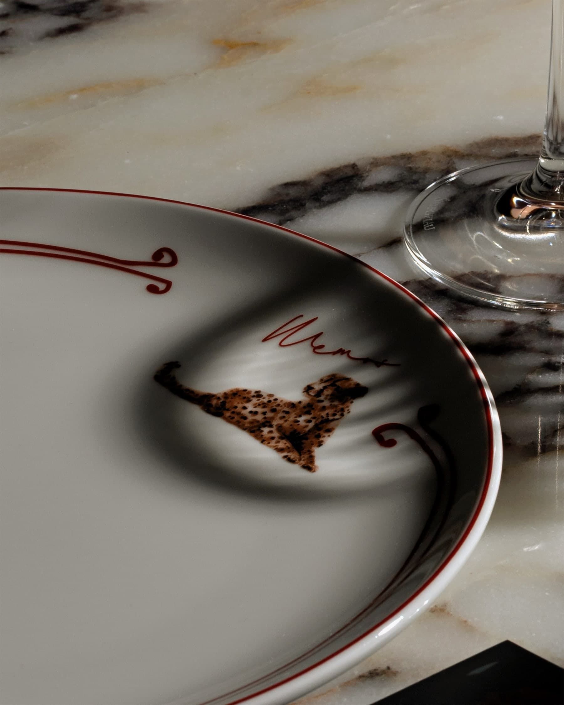 Close-up of a MEMOS branded plate with cheetah motif on a marble table