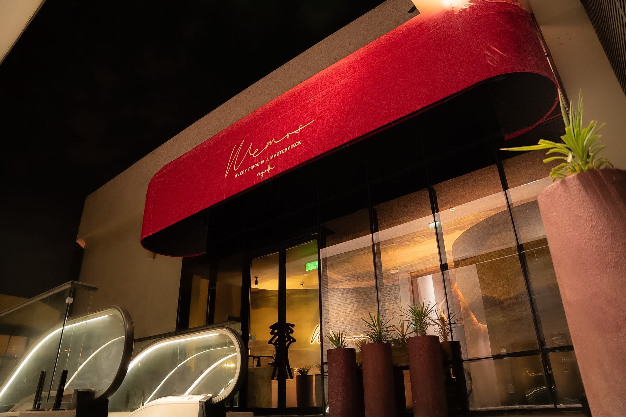MEMOS storefront illuminated at night with its red signature awning in Riyadh